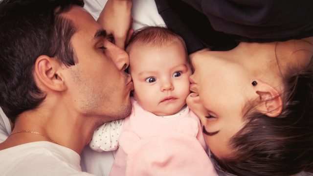 loving-mom-and-dad-kiss-adorable-confused-baby.jpg