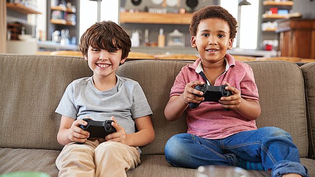 two-boys-sitting-on-sofa-in-lounge-playing-video-PMKWFD5_150.jpg